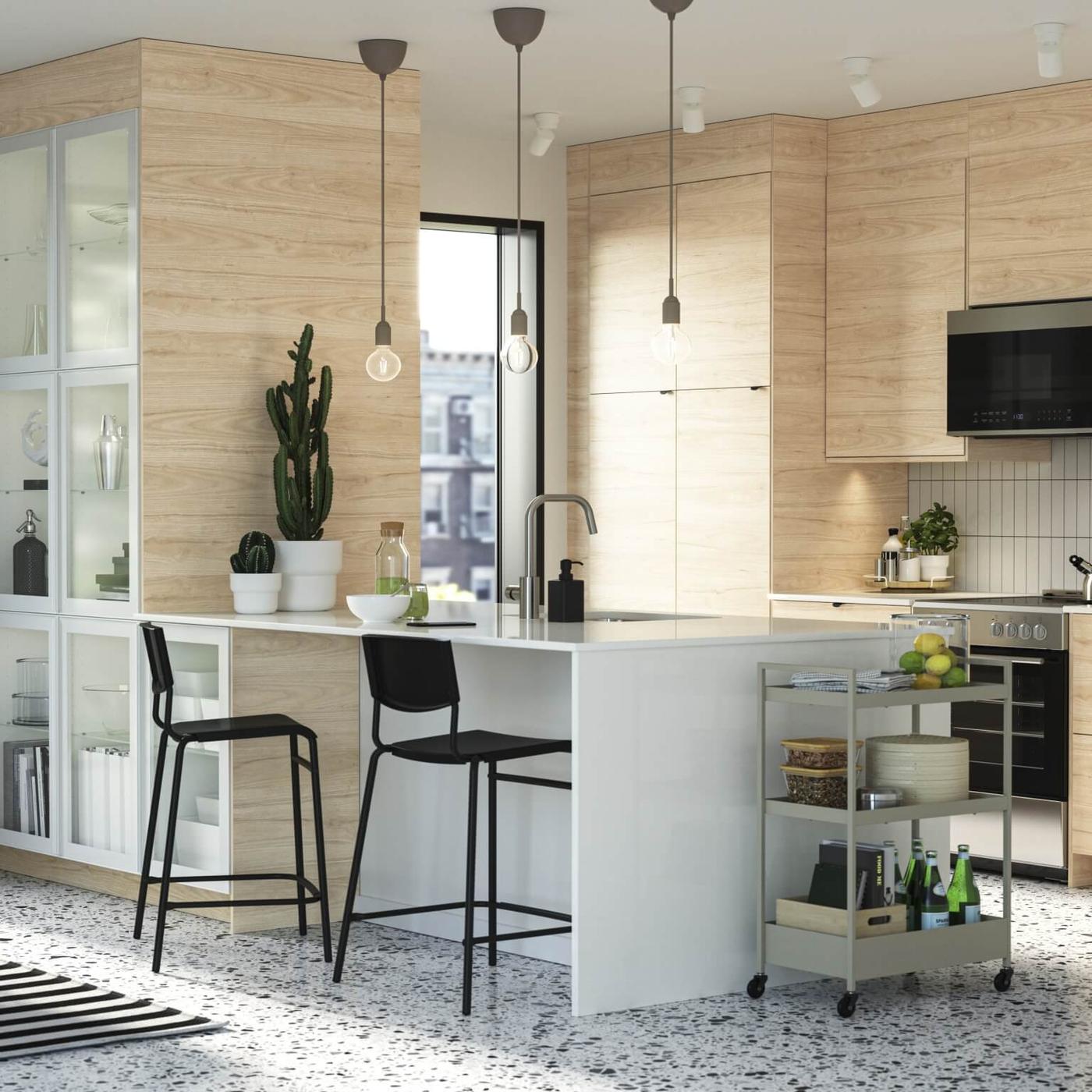 Modern kitchen with light wood cabinets, island seating and stainless appliances.