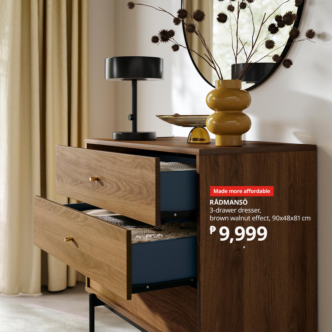 Modern walnut-effect 3-drawer dresser with two drawers open, styled with a black lamp, yellow vase, mirror, and dried branches; ₱9,999.