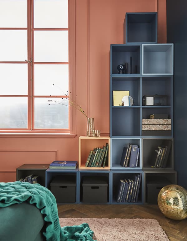 Modular cabinets like EKET from IKEA make it easy to build custom wall storage like this reverse L-shape against a corner. Shades of blue and grey tie the look together while keeping things interesting. A pop of light orange is playful, too.