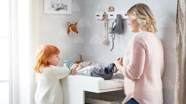 Mom with toddler, changing baby on a changing table.