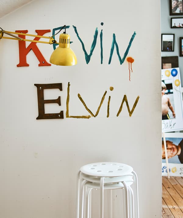 مقاعد مكدّسة بجانب حائط مع الأسمين Kevin وElvin  مطبوعين عليه ومصباح حائط أصفر.