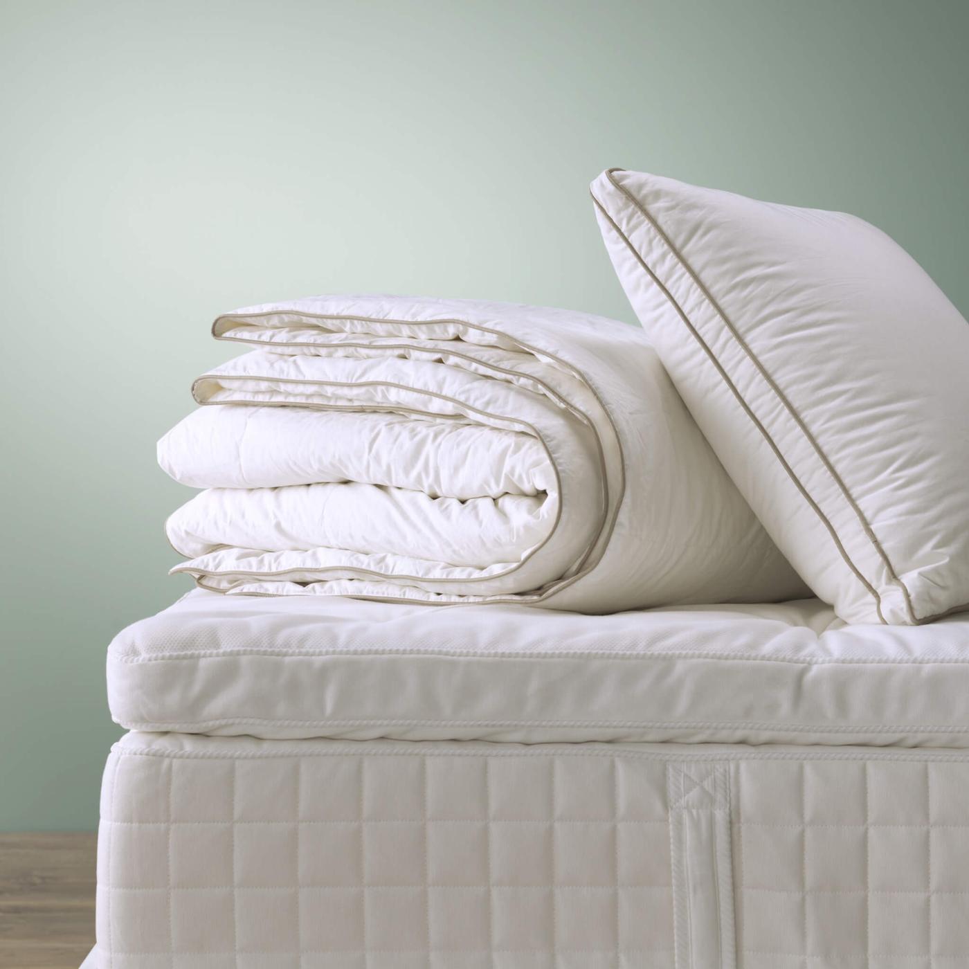 مرتبة عليها مفارش سرير بيضاء مكدسة فوقها.
