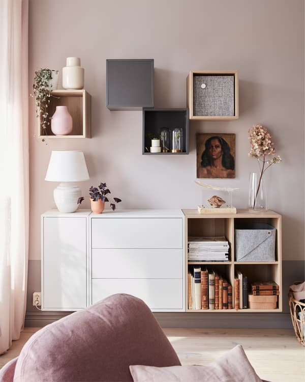 Mueble EKET teñido de blanco, con plantas y  una lámpara colocada encima, situado en una sala con un sillón reclinable.