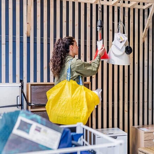 Mujer que lleva una bolsa de compras IKEA amarilla buscando artículos a la venta en el departamento As-is.