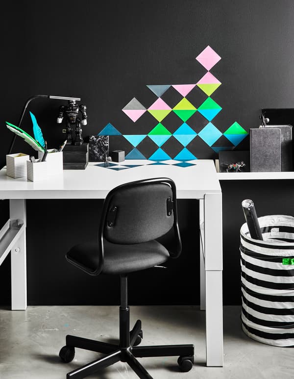 Multi-coloured triangular stickers are arranged decoratively on a wall and on a kid’s desk.