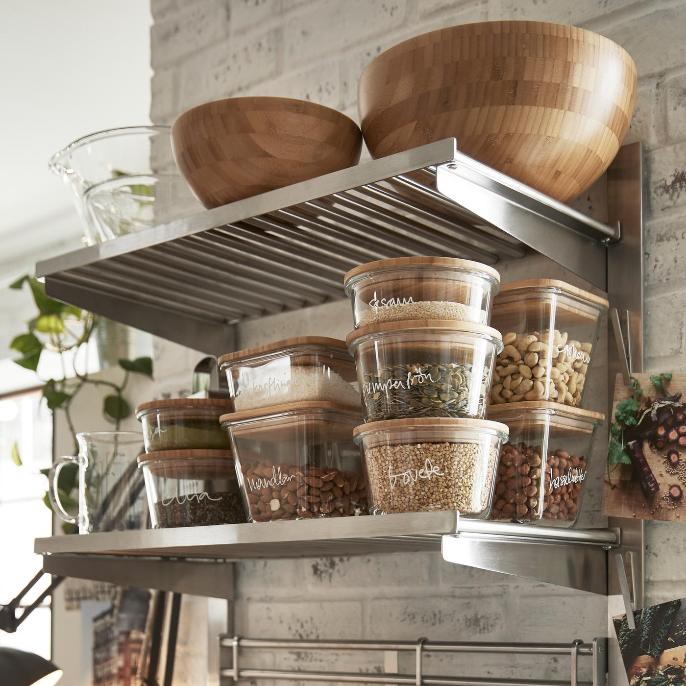 Nahaufnahme einer KUNGSFORS Aufhängeschiene mit Böden/Wandgitter, auf der Geschirr und Trockenvorräte stehen.