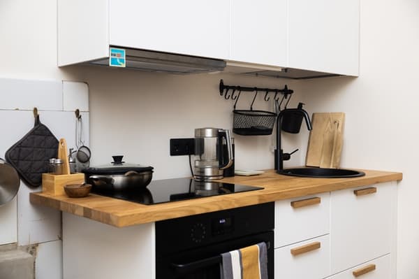 Narrow kitchen with a sink by the window, plants on the windowsill and a functional work area.