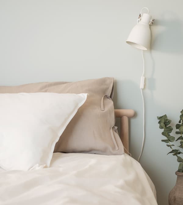 Natural linen pillowcases and a quilt cover in a bedroom with light green walls