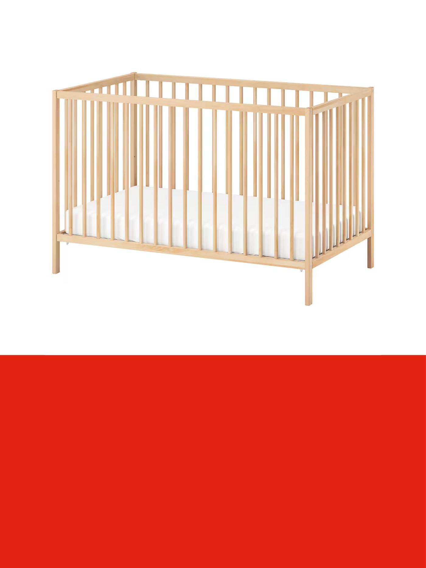 Natural wood cot bed with vertical slats and a white mattress, displayed against a light background above a red promotional banner.