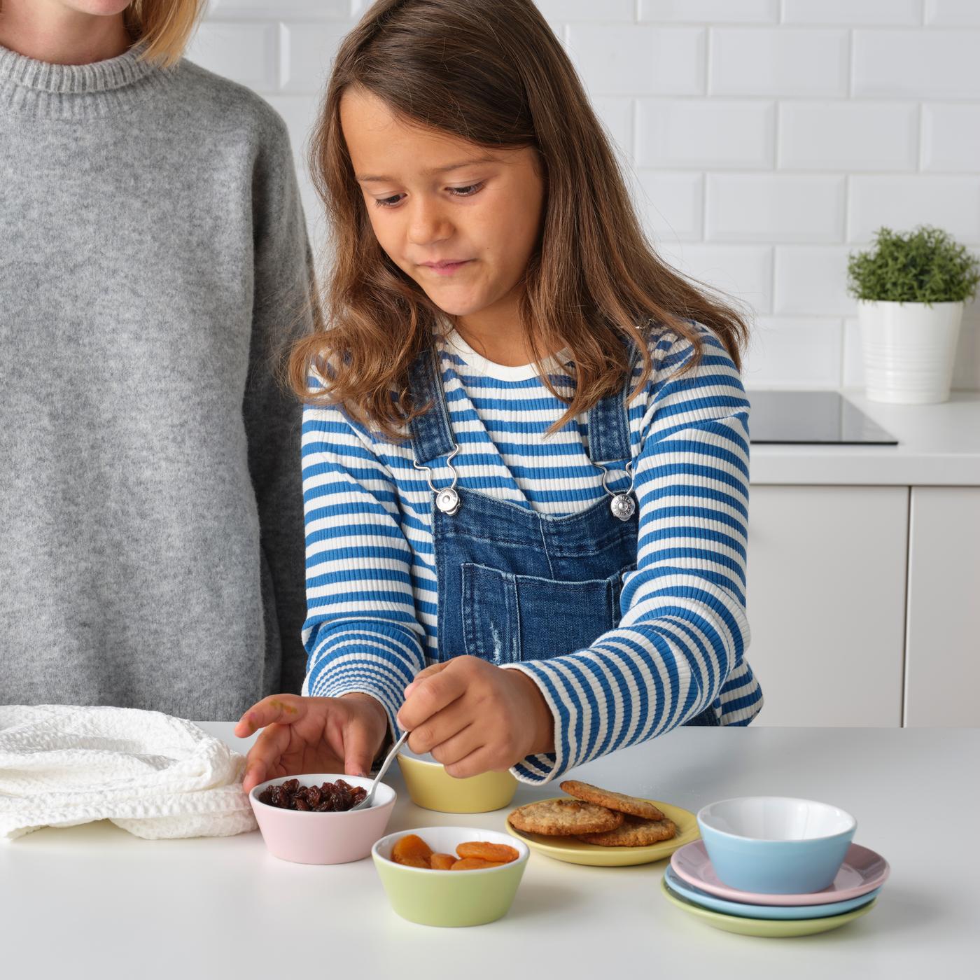 Niña con polera a rayas cocinando con pequeños bowls IKEA de colores.