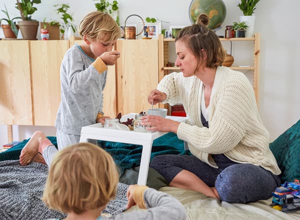 Nina und ihre zwei Kinder frühstücken mit Holzschränken im Hintergrund, u. a. mit KLIPSK Tablett weiß.