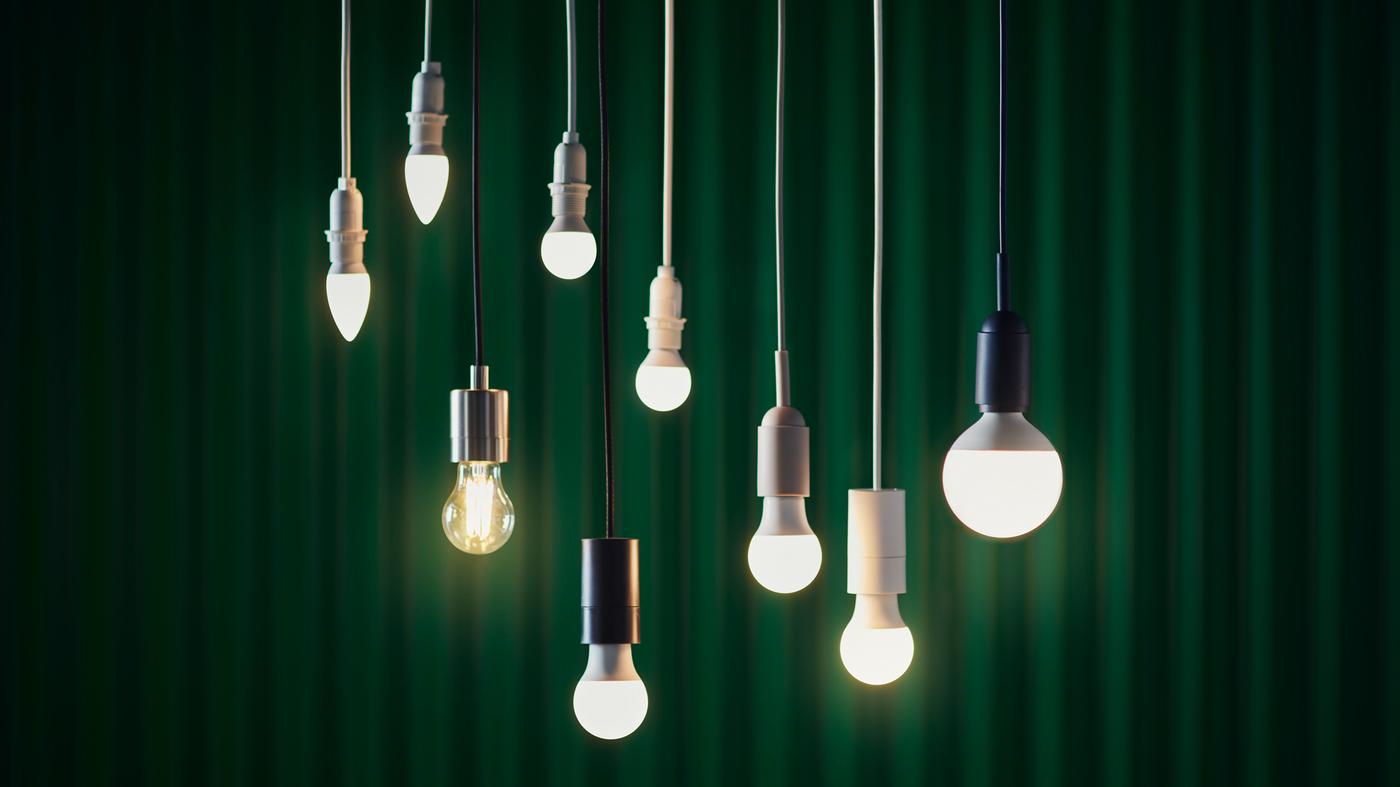 Nine SOLHETTA LED bulbs are hanging from the ceiling, in front of a green curtain.