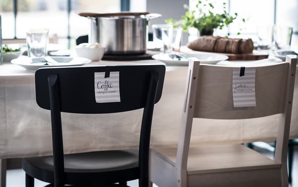 Notes of different tasks taped to the back of chairs at the dining table, telling each guest what they can help with.
