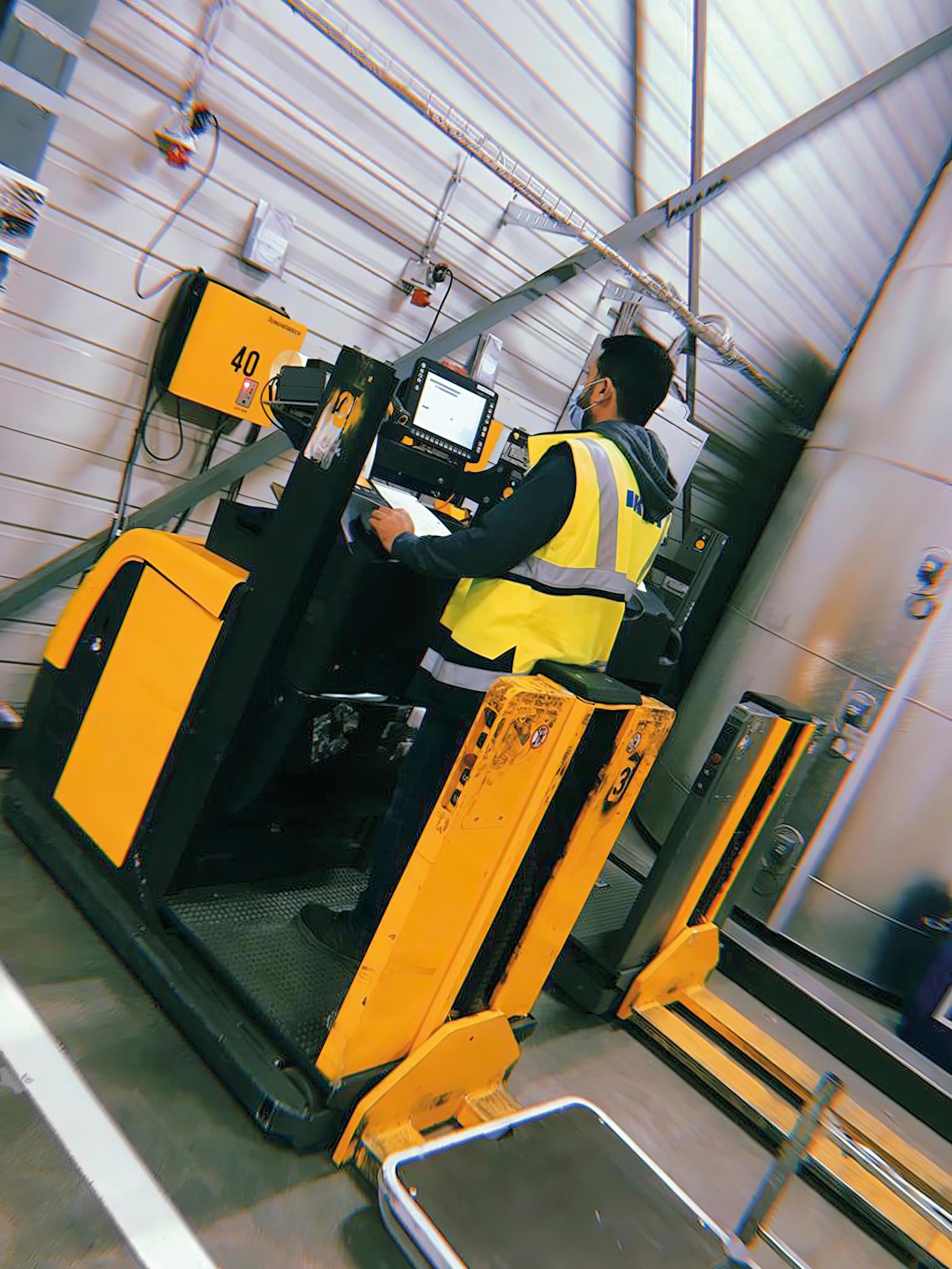 Odai, ein Flüchtling aus dem Irak und jetzt IKEA Mitarbeiter, trägt eine gelbe Weste und schaut auf den Bildschirm einer Maschine.