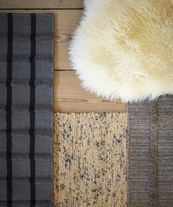 Off white RENS sheepskin layered with beige and grey rugs on a light brown floor