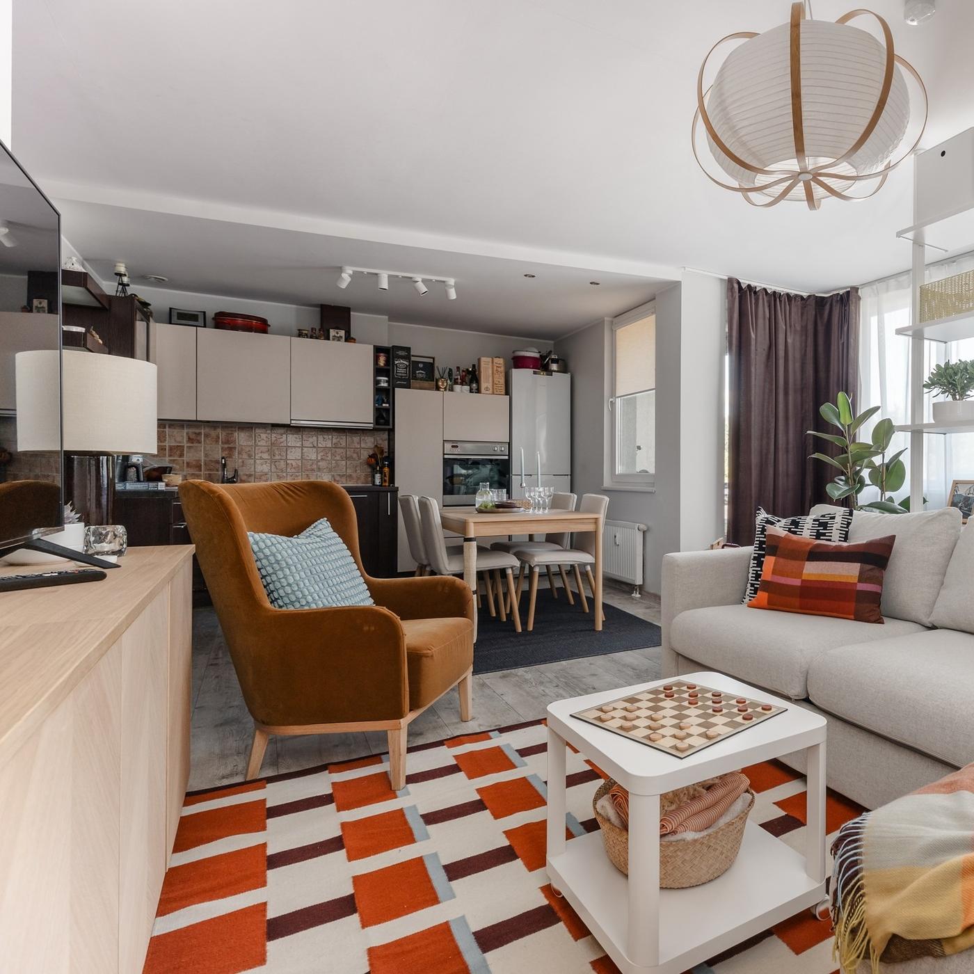 Open-plan living and dining room with flexible seating, layered lighting, warm wood finishes and colourful rugs.