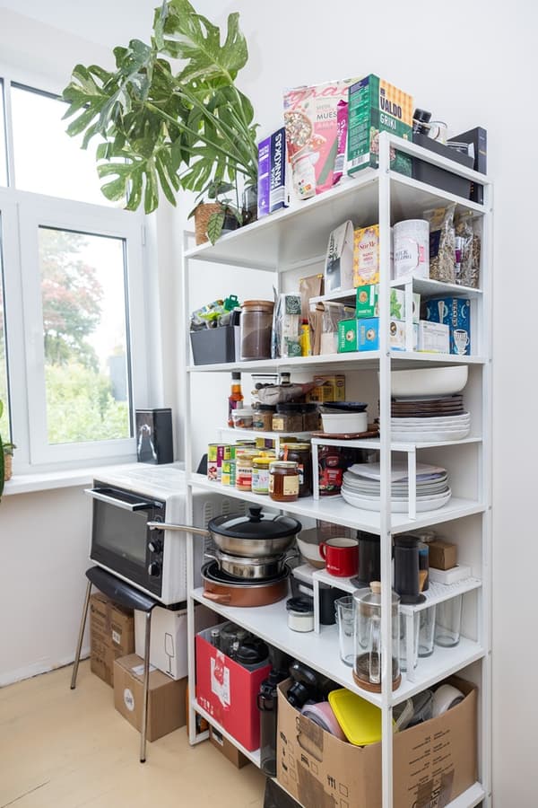 Open shelving unit with food supplies and kitchen items used as a pantry.