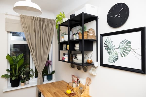 Open wall shelves in a kitchen holding dishes, food items and decorative accents.