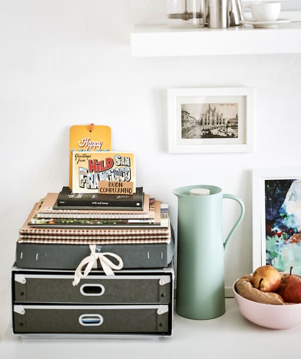 Organiseur de bureau, thermos, coupe de fruits et tableaux disposés avec art.