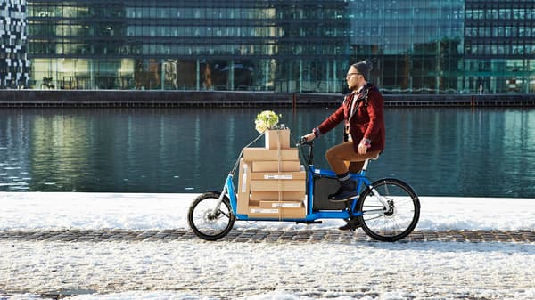 Osoba rozvážející balíky IKEA na kole u řeky
