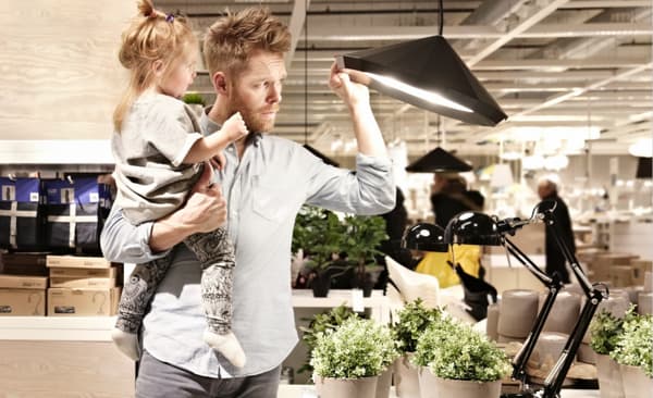 Otac drži ćerku u naručju dok gleda IKEA visilice u robnoj kući