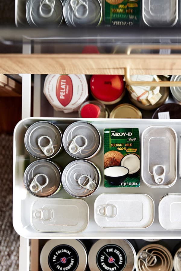 Overhead view of an open kitchen drawer of dry goods. It’s segmented using shelf inserts and storage containers.