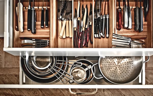 Overhead view of open kitchen drawers that reveal pots and pans, and lots of utensils in drawer inserts.