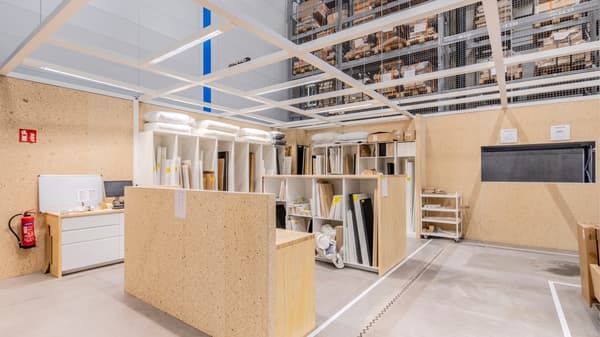 Overzicht van een georganiseerde hergebruikzone met rekken, werkbladen en opslag voor herbruikbare materialen.