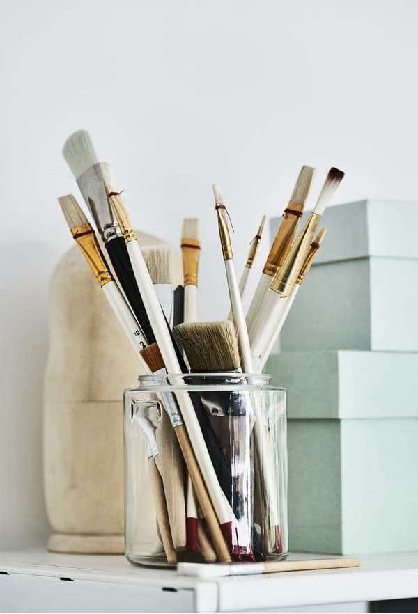 Paintbrushes stored in a glass jar.
