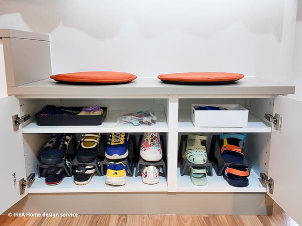 Pairs of shoes stored in a brown and white combination METOD modular storage in a living room in Singapore, designed by IKEA Home design service
