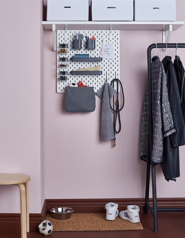 Panneau perforé SKÅDIS rattaché à une tablette dans un hall d’entrée, avec accessoires pour les affaires du chien – jouets, laisses, bonbons et brosses