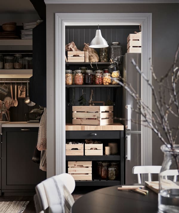 Pantry-like kitchen section; kitchen island with wooden crates snugly placed in corner underneath shelves with pickle jars.
