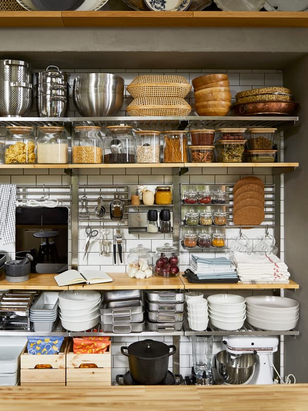 Pantry-style, open-storage kitchen wall with KUNGSFORS shelves, filled with dry goods in jars and cooking accessories.