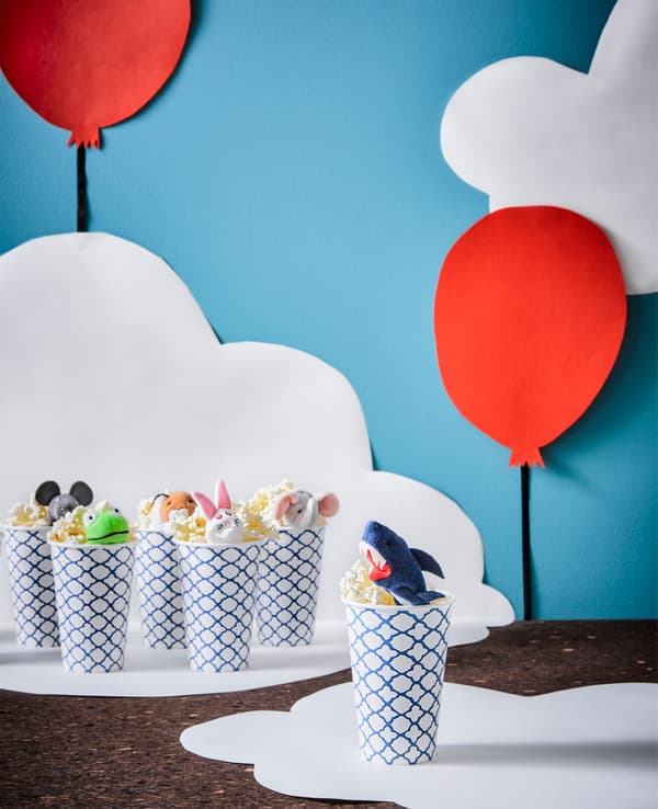 Paper cups are filled with popcorn and topped with a finger puppet.