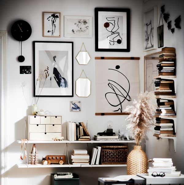 Pared decorada con muchos accesorios como cuadros, espejos, relojes, libros y más.