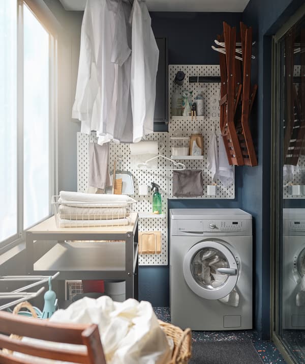 Part of a balcony turned into a compact wash house, with washing machine, wall-mounted accessories and hang-drying clothes.