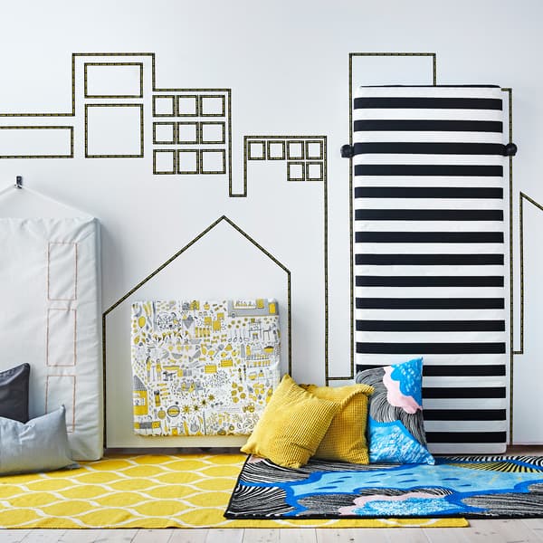 Paysage de gratte-ciels créé avec du ruban adhésif et de matelas recouverts de textiles redressés contre le mur.