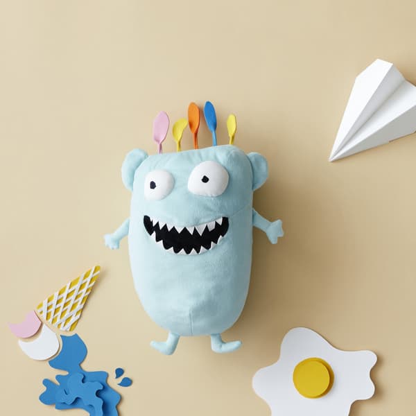 Peluche en forme de monstre bleu dans un décor en papier amusant.