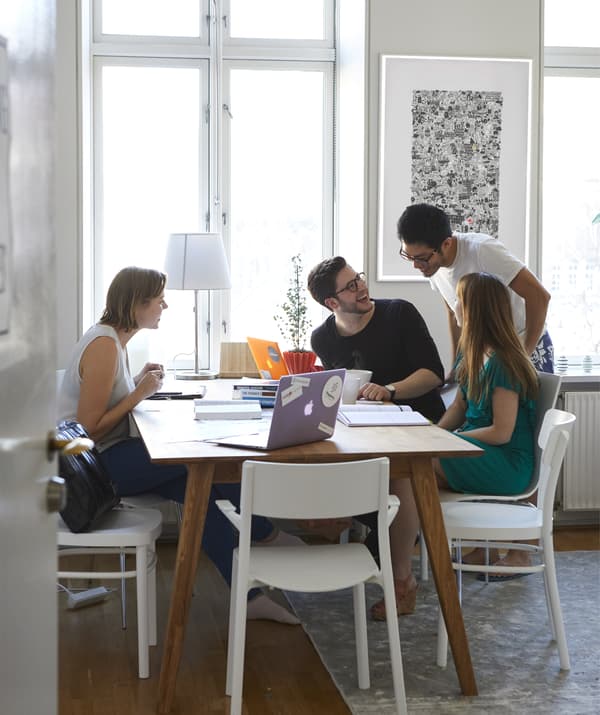 People gathered around a table with laptops and notebooks.