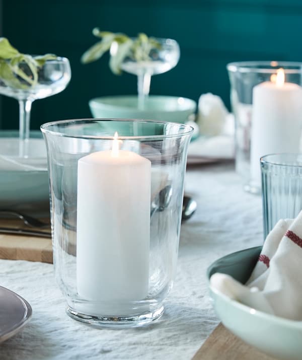 Per creare un'atmosfera rilassante in tavola, disponi un cero senza profumo FENOMEN bianco di IKEA in un vaso/lanterna.