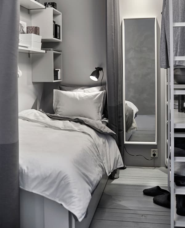Petit coin à dormir blanc et gris créé dans un espace partagé avec armoire.