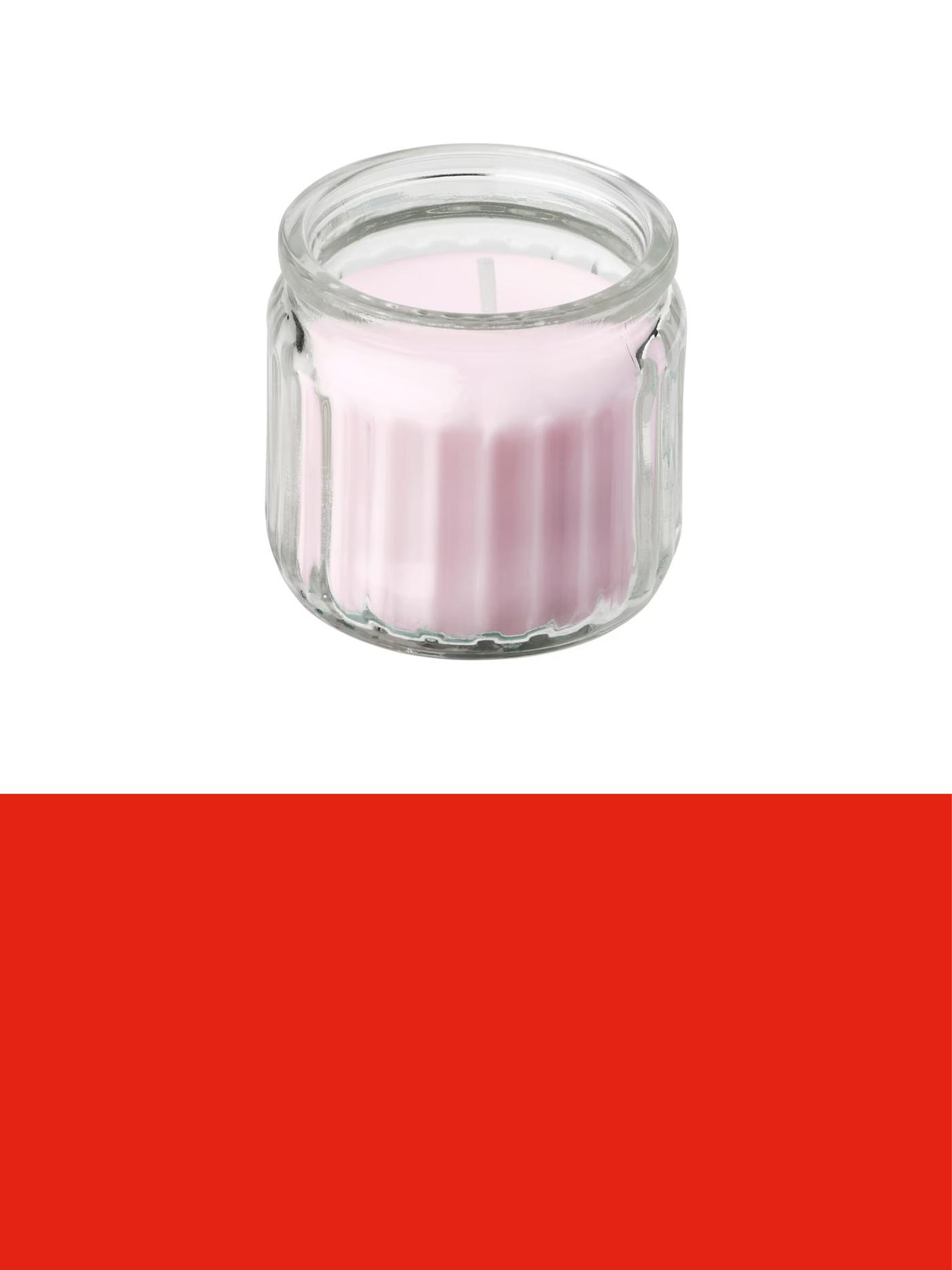 Petite bougie parfumée rose dans un photophore en verre transparent, présentée sur un fond clair au-dessus d’une bannière promotionnelle rouge.