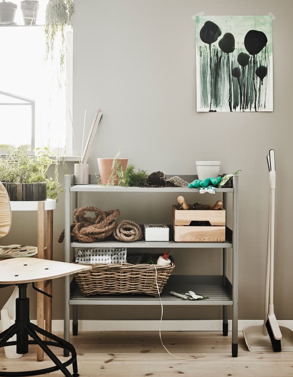 Petite étagère métallique faisant office d’établi de jardinage, dans un coin de la pièce.