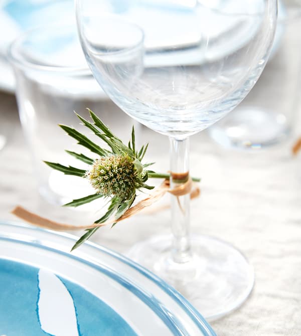 Petite fleur attachée avec de la ficelle au pied d'un verre à vin rouge.