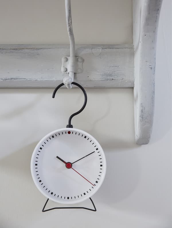 Petite horloge suspendue à une patère peinte.