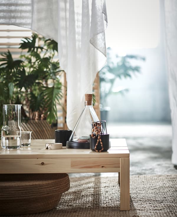 Petits bibelots et cône en verre posés sur un banc en bois.