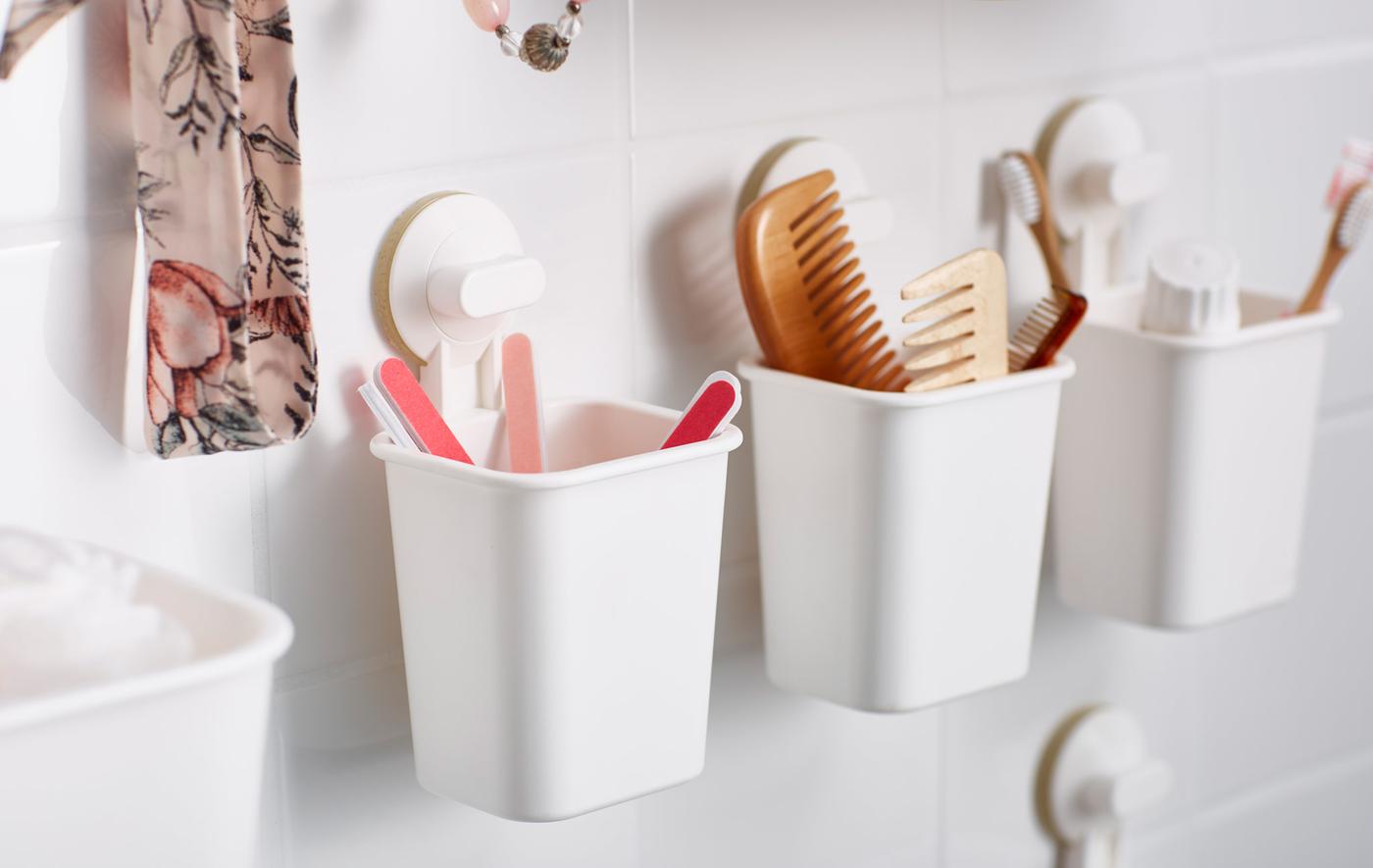 Petits récipients en plastique fixés par ventouse au mur de la salle de bain, comme rangements pour les articles de toilette et les accessoires.