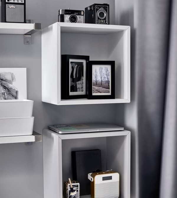 Photos, appareils photo et installation audio sont rangés sur une tablette au-dessus du lit.
