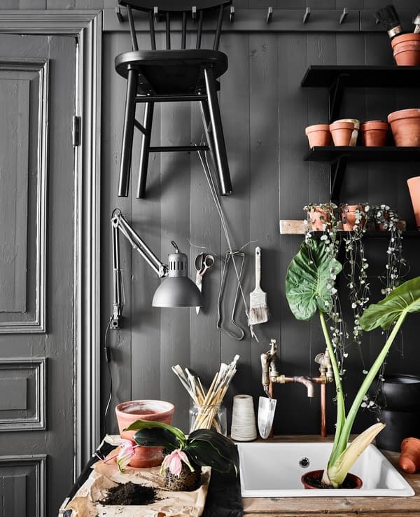 Piccola area giardino in cucina realizzata con un lavello nuovo e un vecchio tavolo di legno contro la parete, mensole per vasi e utensili da giardinaggio - IKEA.