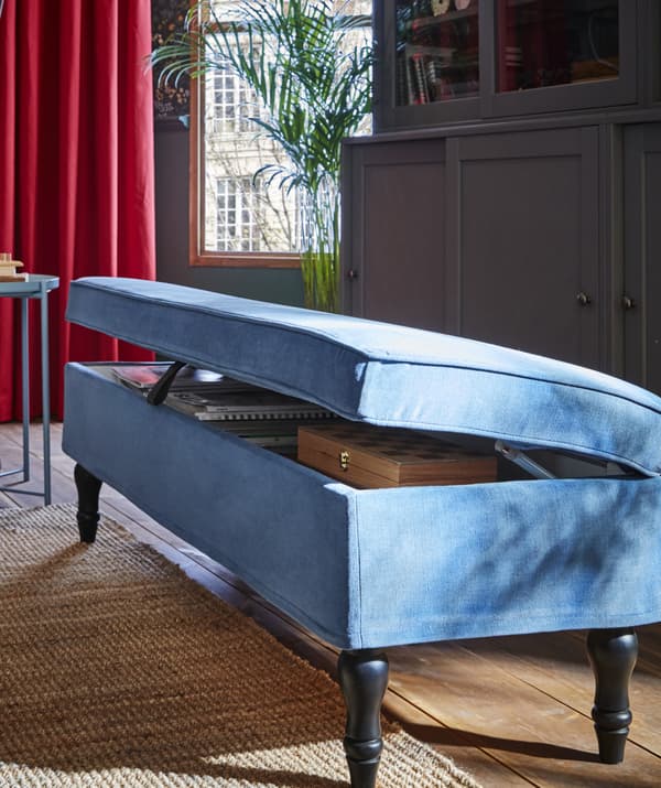 Picture of light blue bench with lid partially raised to show items stored within.